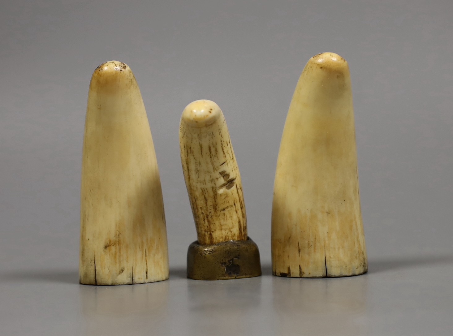 Three 19th century scrimshaw sperm whale teeth, tallest 10cm